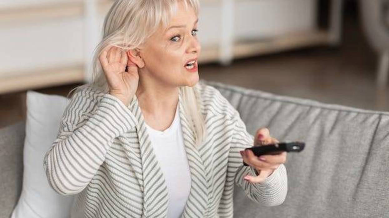 Woman holding hand to ear to hear the TV
