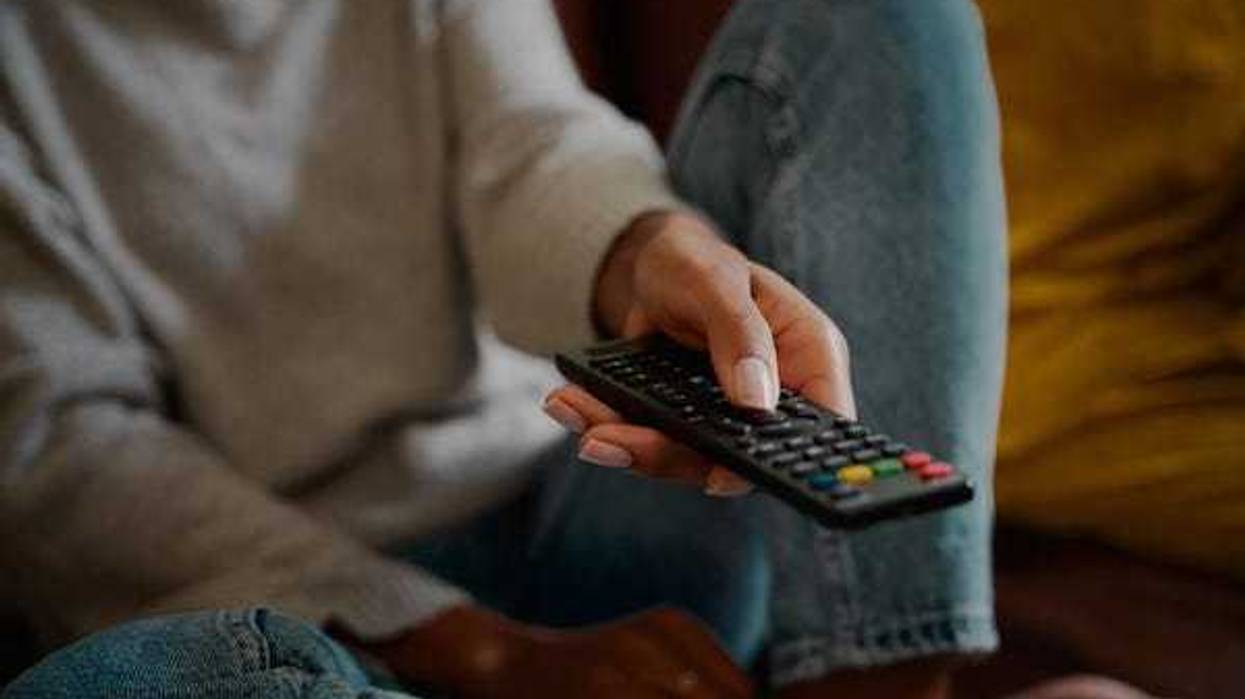 Woman holding remote control and changing channel at home watching television alone