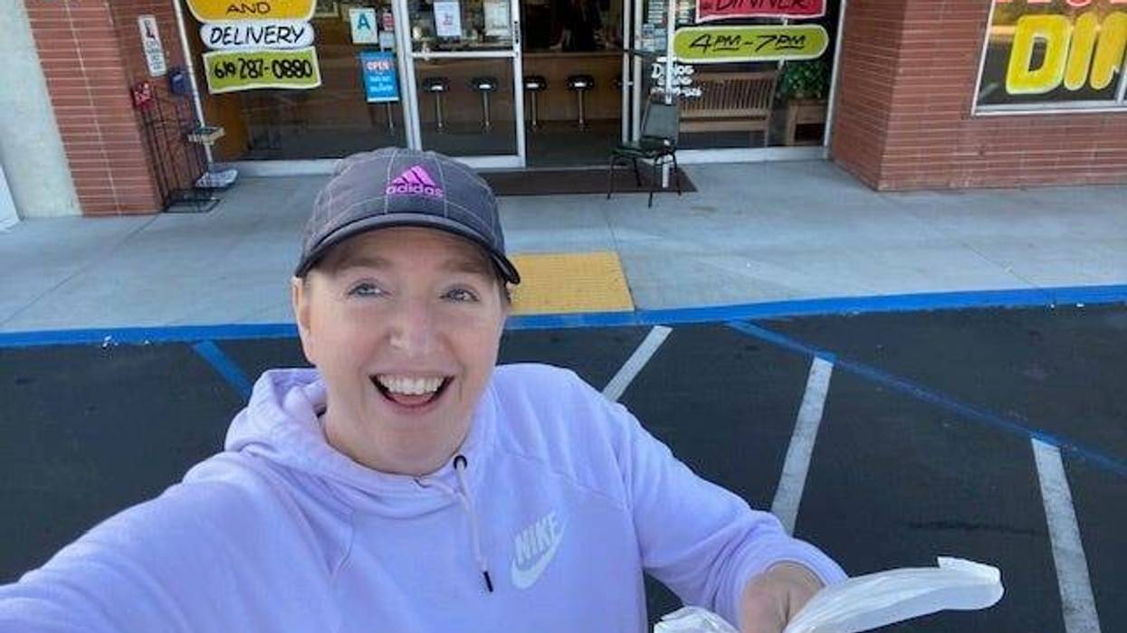 woman holding take-out in front of restaurant