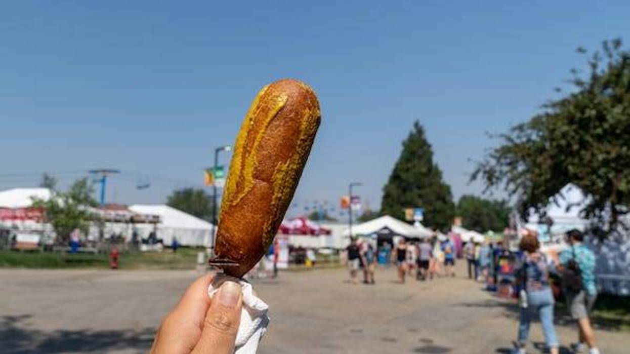 Woman holding up a corndog with mustard at a fair