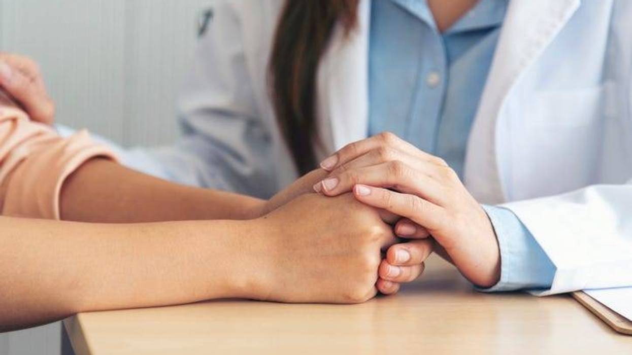 woman holds hands with doctor in medical office