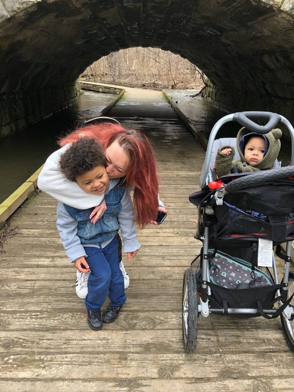 Woman hugging little boy next to little boy in stroller