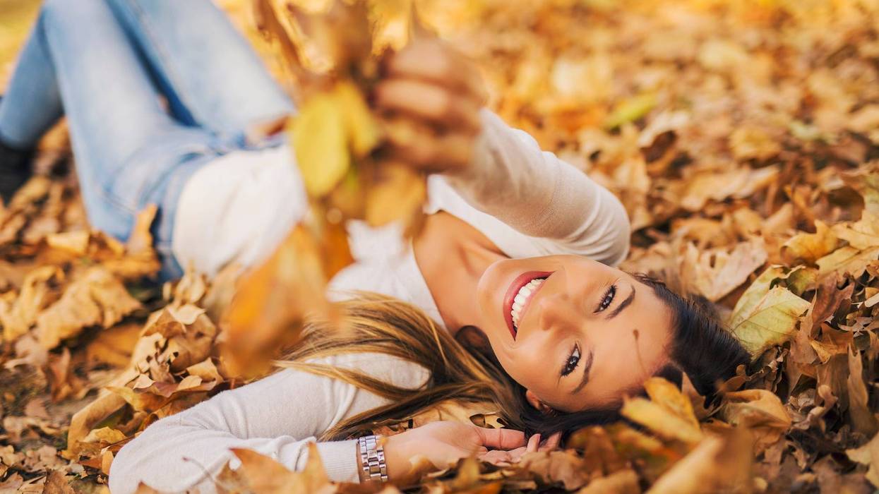 Woman laying down on the pile of leafs and playing