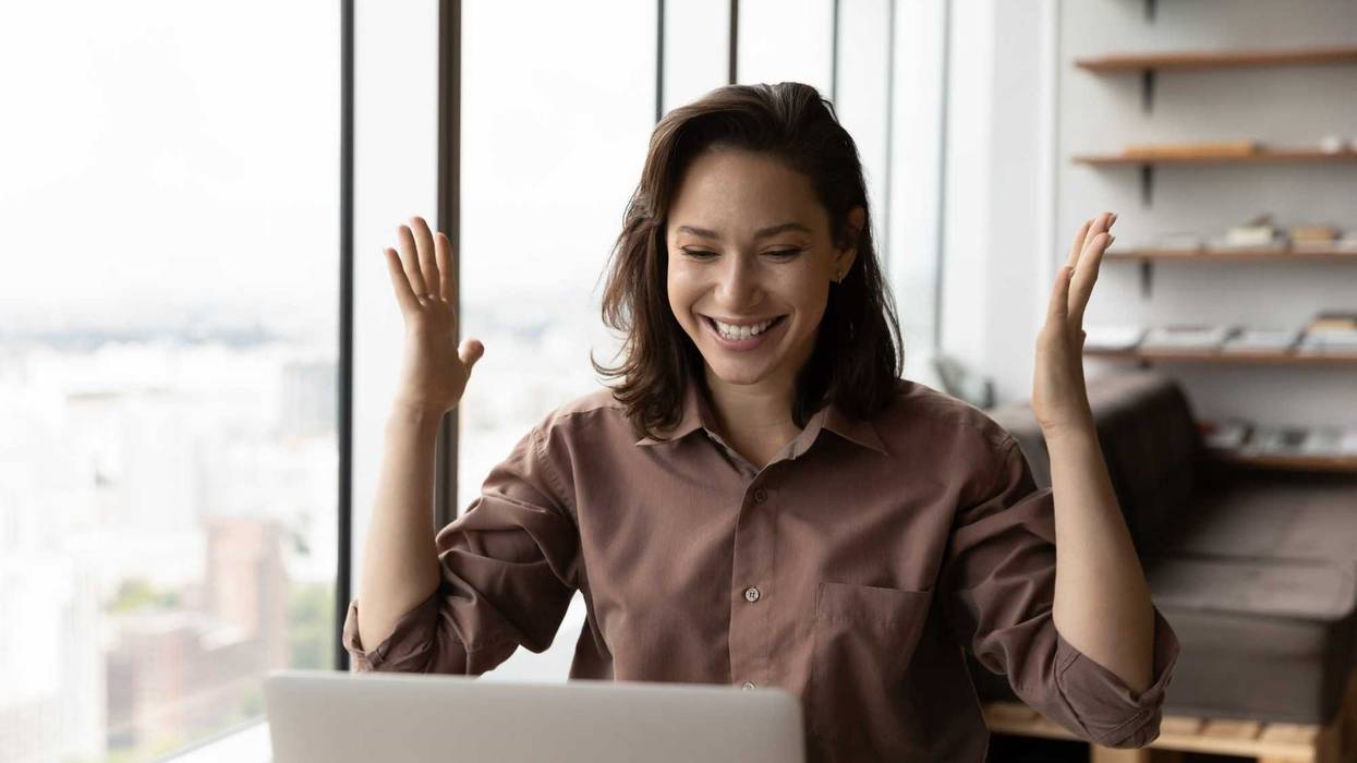 Woman looking happily at computer screen.