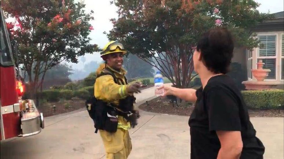woman offering bottle of water to firefighter