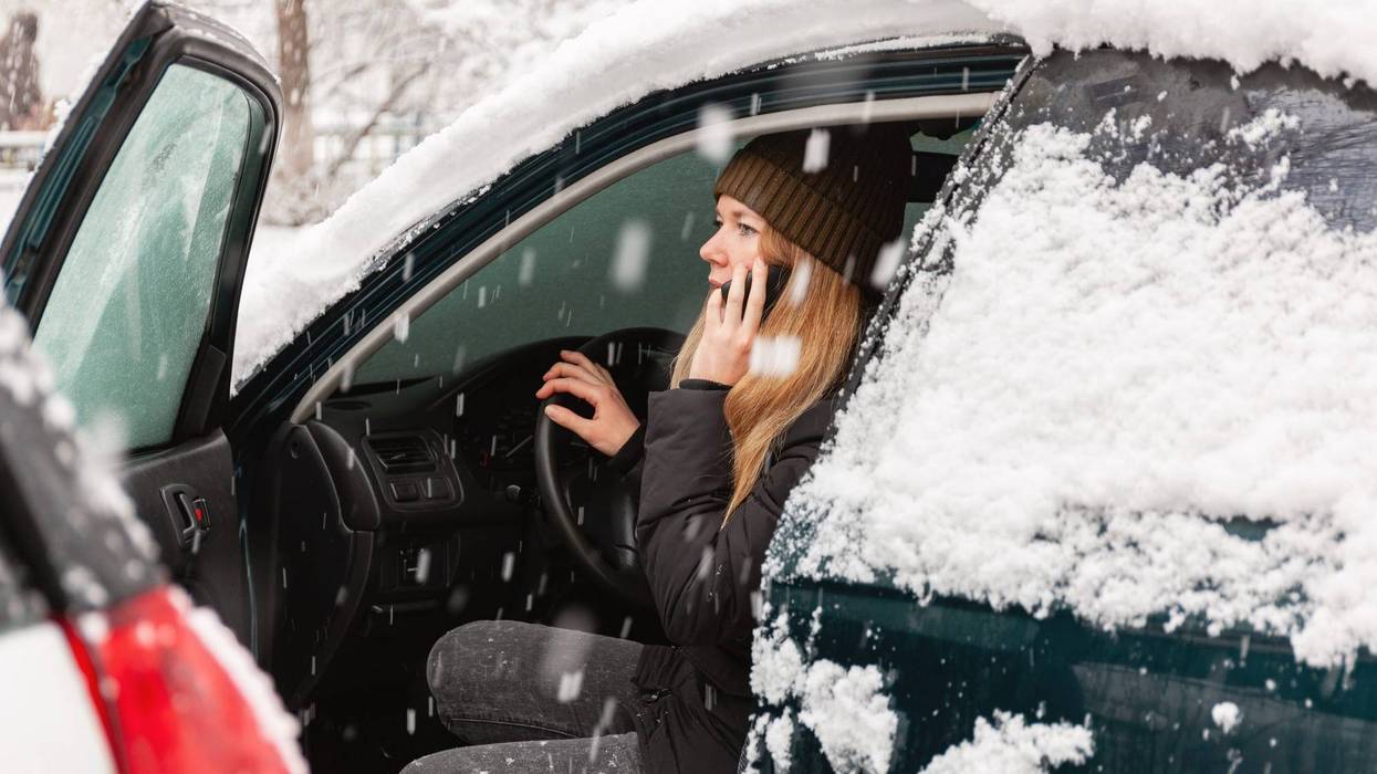Woman on the phone in car covered in snow
