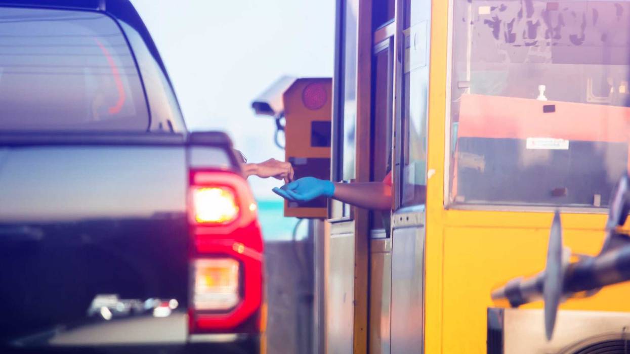 Woman pays money to a cashier for a toll road toll gate motorway entrance.