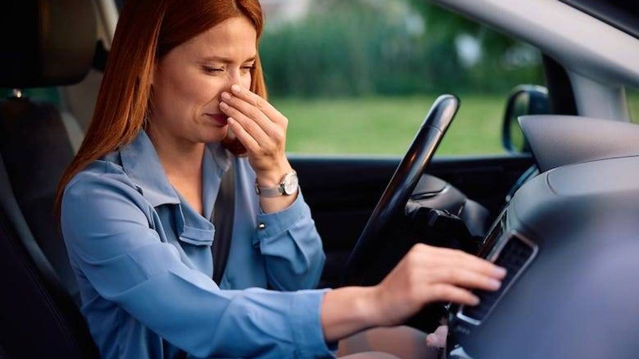 Woman pinching her nose shut while driving her car