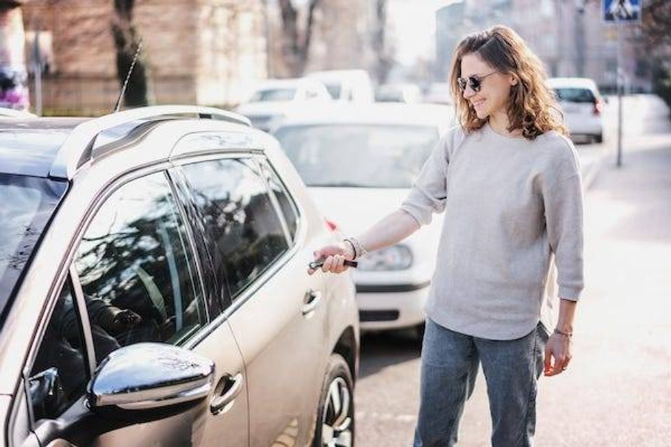 Woman pointing key fob at car