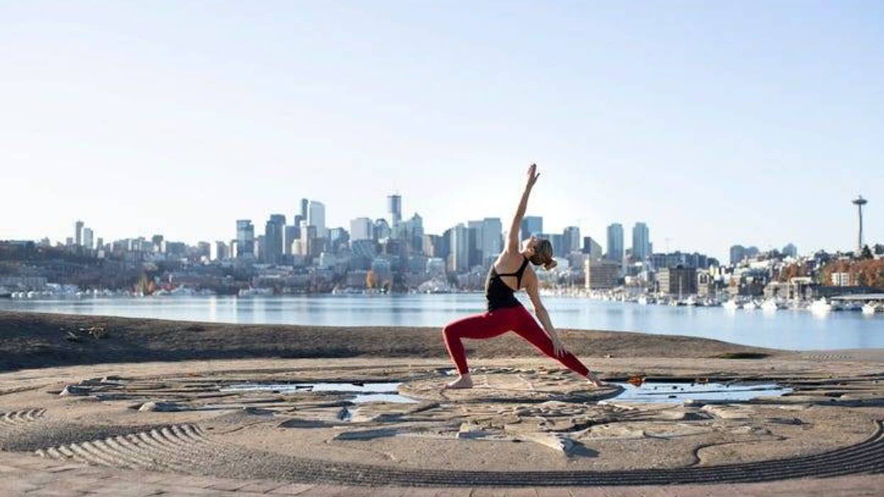 Woman practices yoga against Seattle skyline