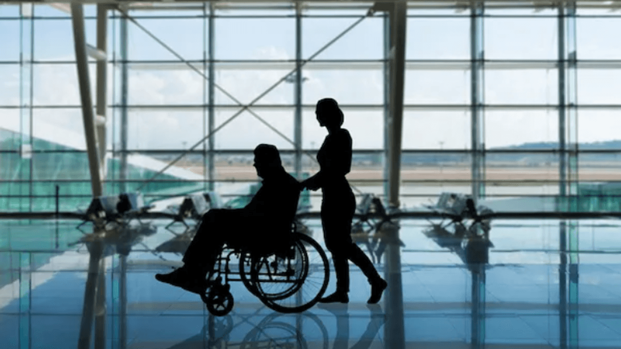 Woman pushing man in a wheelchair through an airport