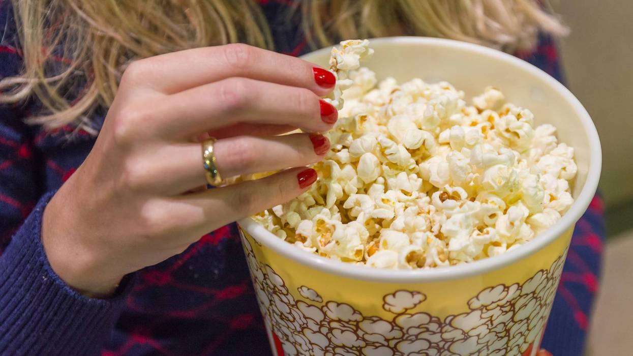 Woman's hand close up, picking up popcorn.
