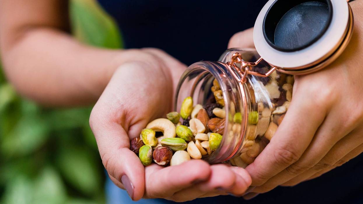 Woman's hand holding glass hermetic pot with mix of nuts
