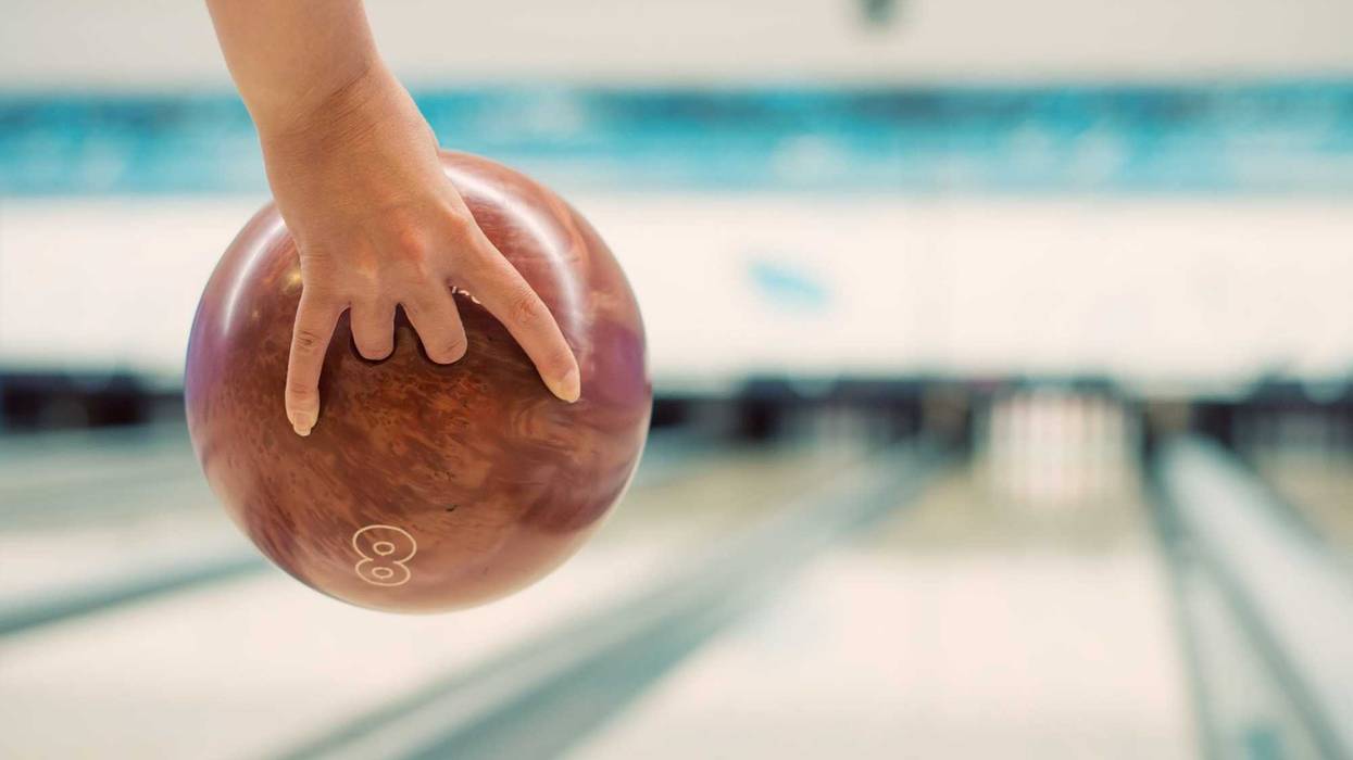 Woman's hand throwing ball in bowling club.