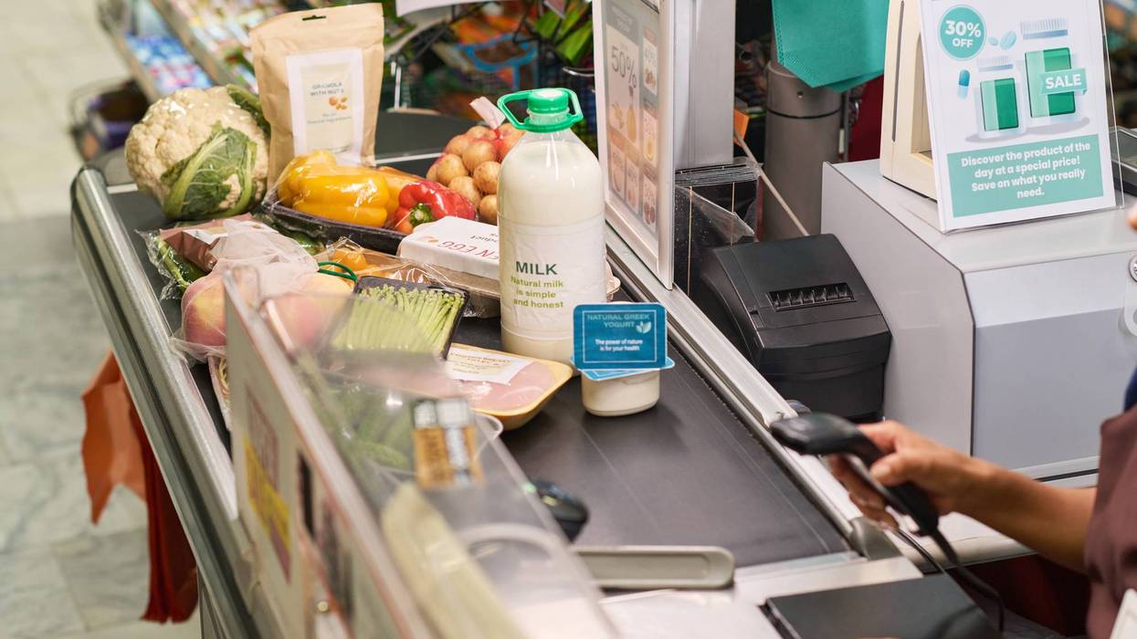 Woman Scanning Groceries on Conveyor in Supermarket
