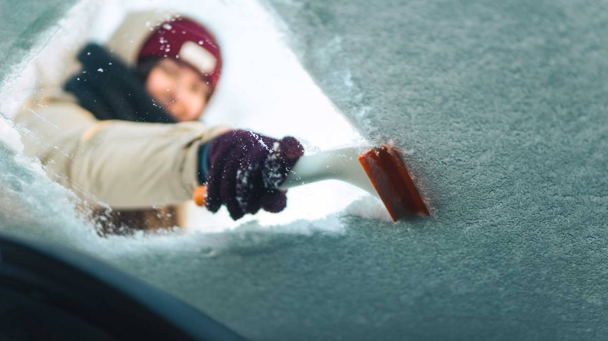 woman scraping snow from windshield