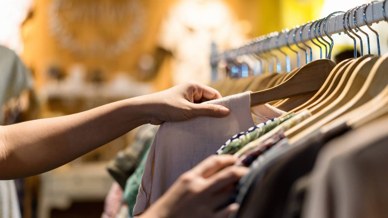 woman selecting shirt from rack of clothes