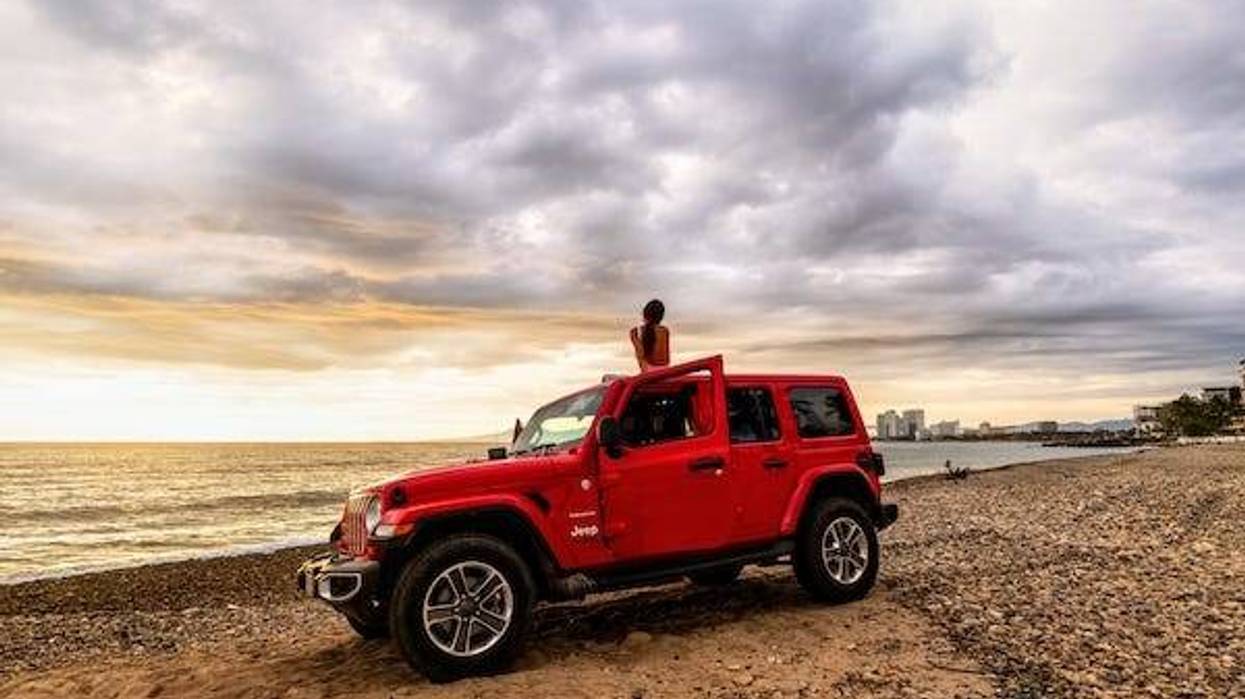 Woman sitting in a Jeep Wrangler on the beach