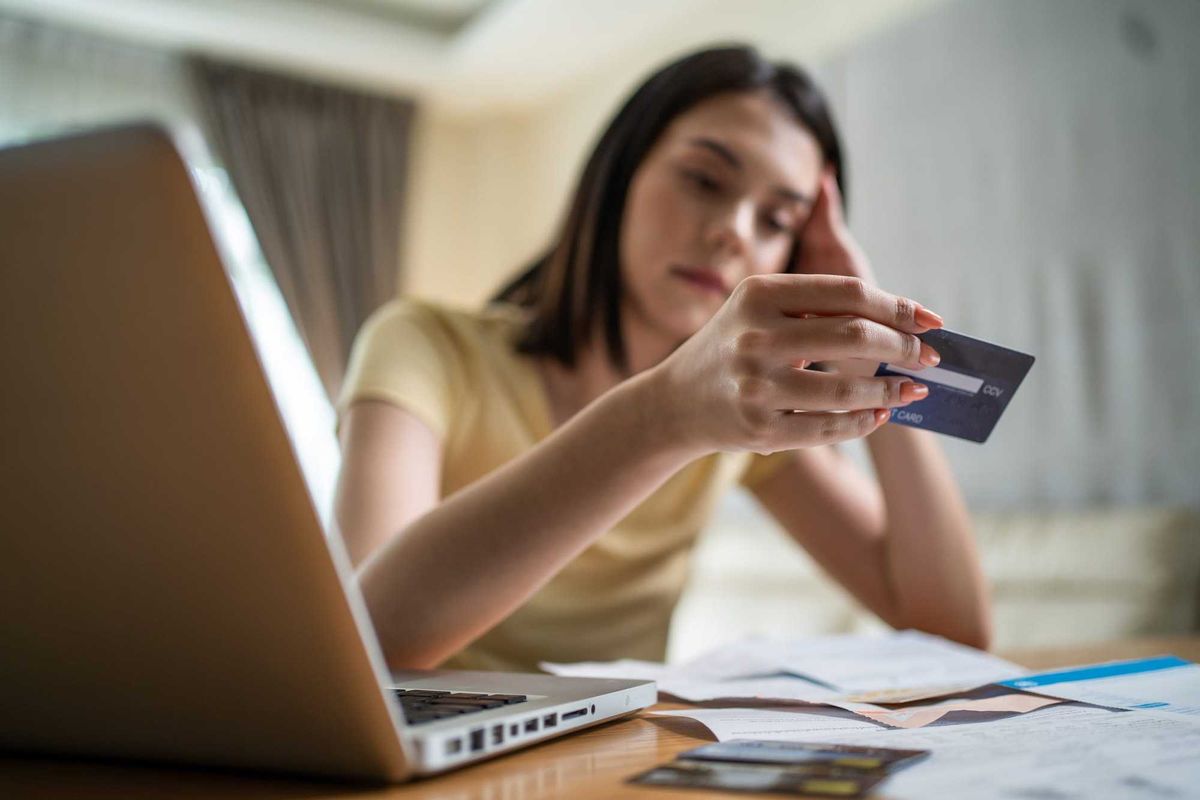 Woman staring at her credit card and bills.