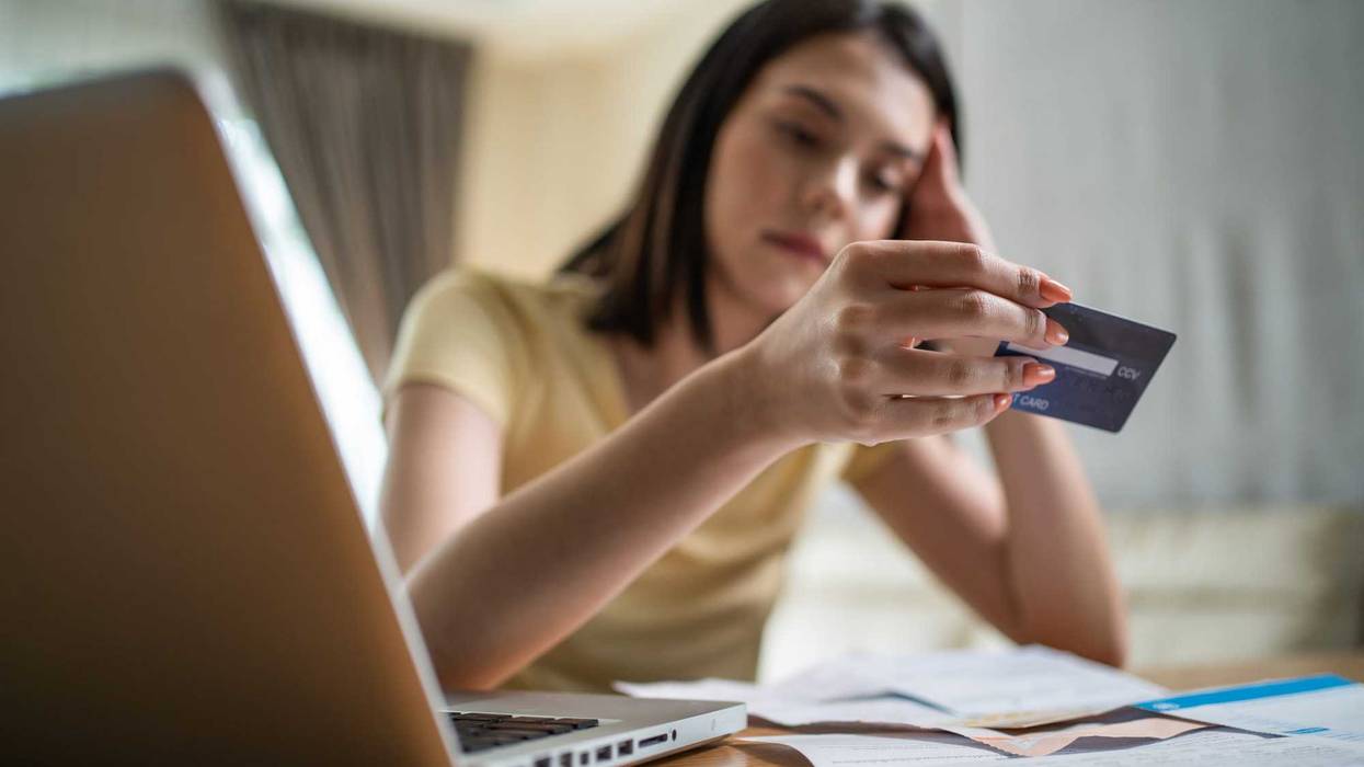 Woman staring at her credit card and bills.