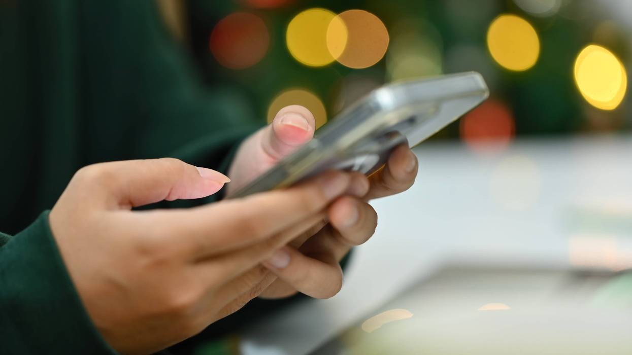 woman typing on smartphone on background of Christmas tree with lights