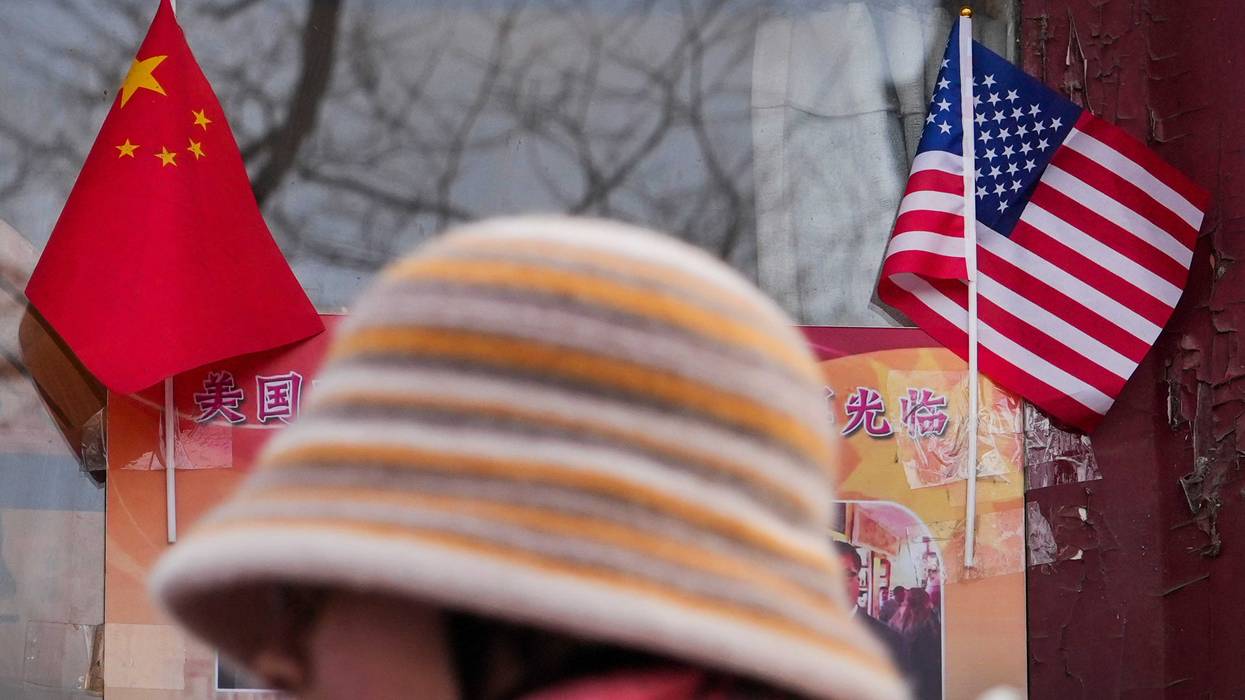 woman walks by the Chinese and U.S. national flags