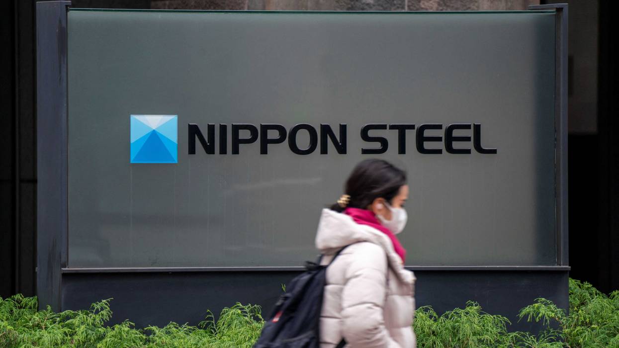 woman walks past the logo of Japan's largest steel manufacturer Nippon Steel corporation
