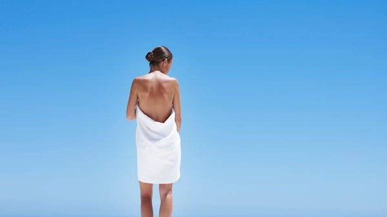 Woman wearing a towel outdoors against an ocean backdrop