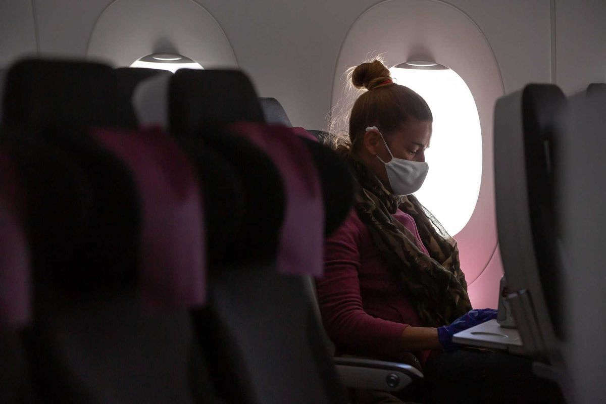 Woman wearing mask on plane stock photo.