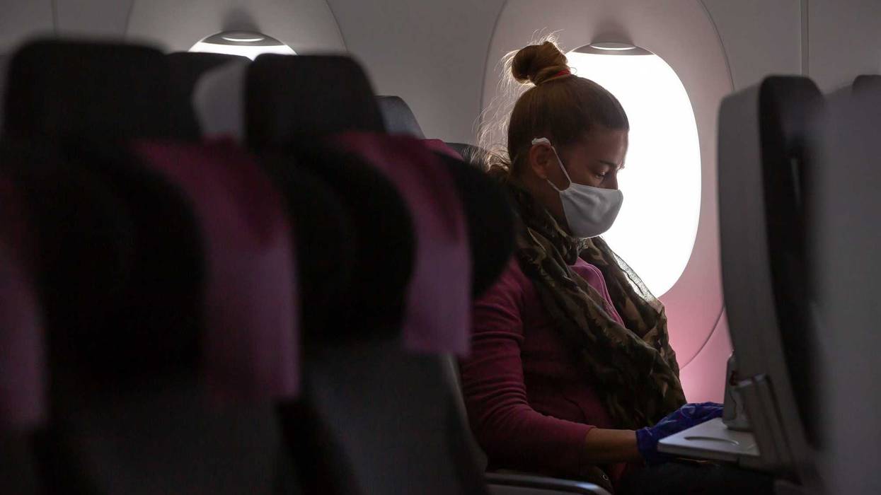 Woman wearing mask on plane stock photo.