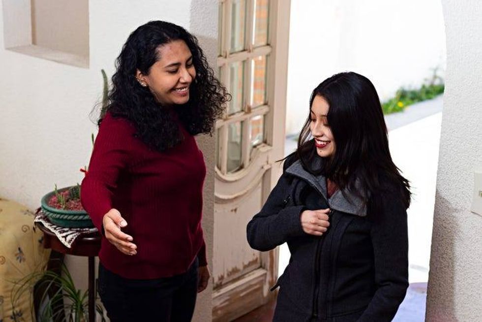 Woman welcoming another woman into her home
