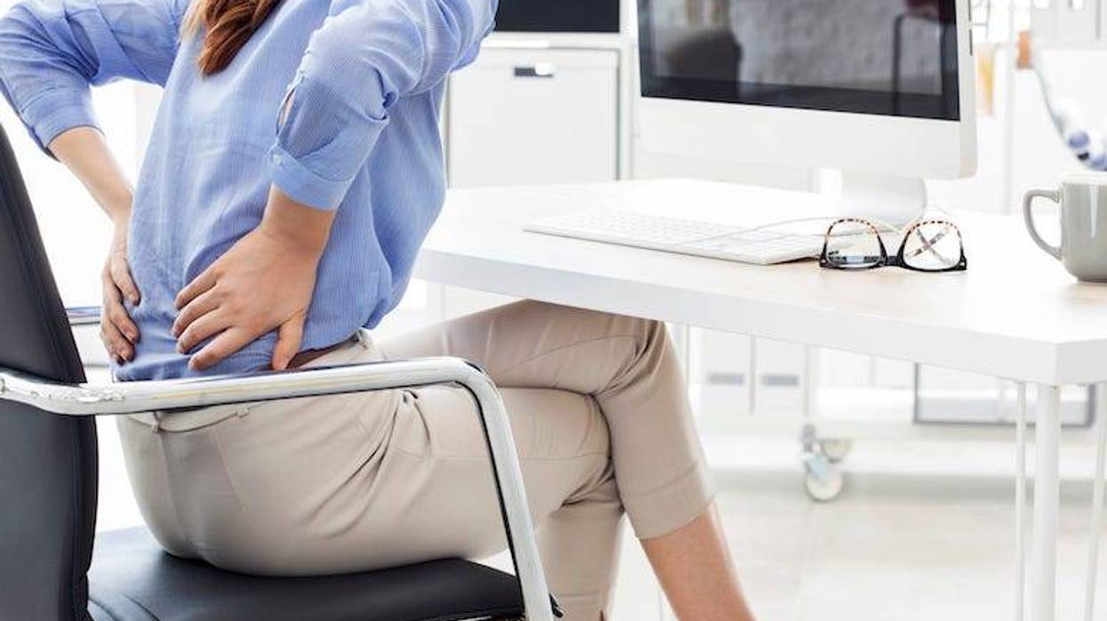 Woman with back pain sitting in office chair