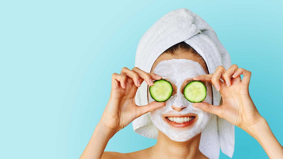 Woman with face mask and cucumbers over her eyes.