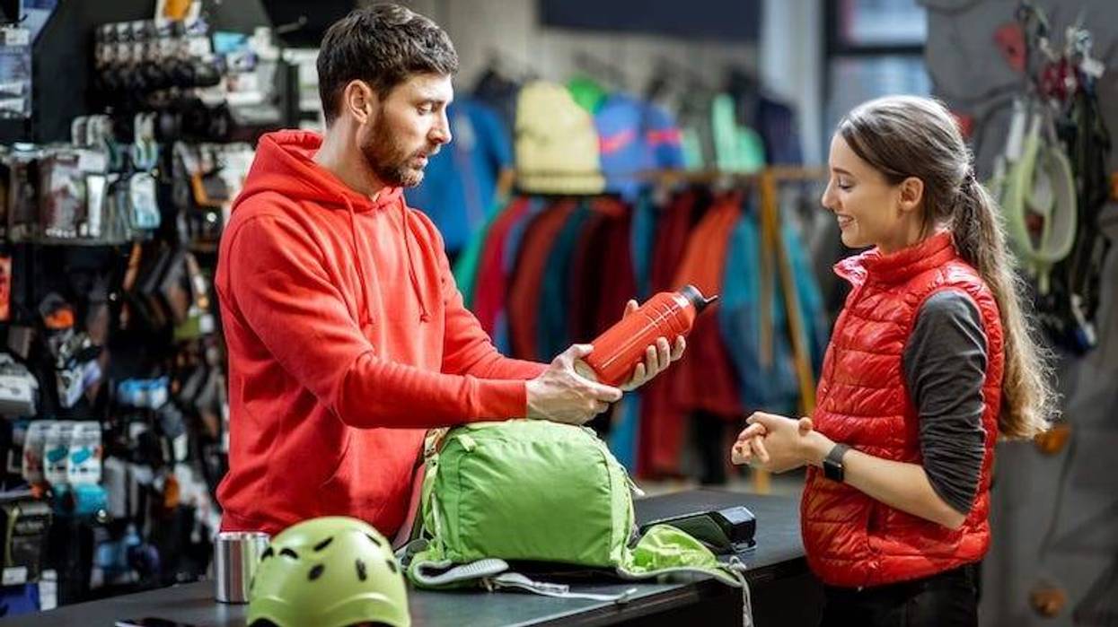 Woman with salesperson at the counter of sports shop
