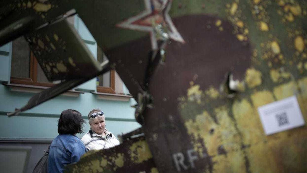 Women chat on the street next to the remnants of a destroyed Russian fighter jet which is part of a display of Russian military hardware that has been put on the street for public viewing in central Kyiv on May 17, 2022 in Kyiv, Ukraine.