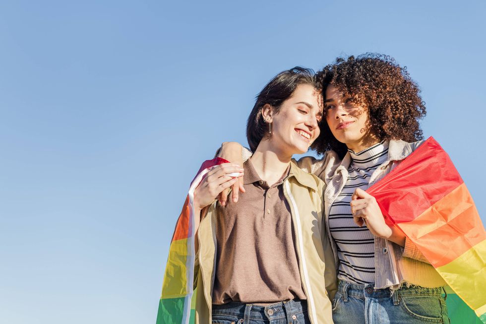 women embracing with a rainbow flag