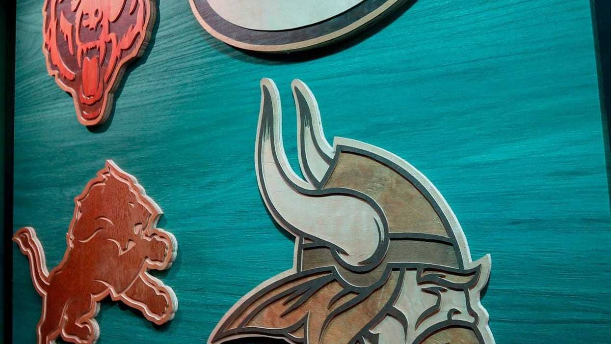 Wooden logos for the NFC North teams, made by Milwaukee artist Ike Wynter, are seen in the walkway between the green room and the Draft Theater during the 2025 NFL Draft media day preview on Wednesday, April 23, 2025, at the Resch Center in Ashwaubenon, WI. The draft begins at 7 p.m. CT April 24 and runs through April 26.