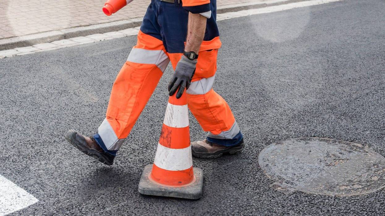 Worker places construction cone on roadway