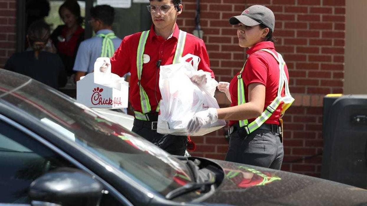 Workers at a Chick-fil-A deliver meals to customers in their vehicles at the drive-up window after the restaurant closed its indoor seating in an effort to curb the spread of the coronavirus pandemic on March 20, 2020 in Pembroke Pines, Florida.