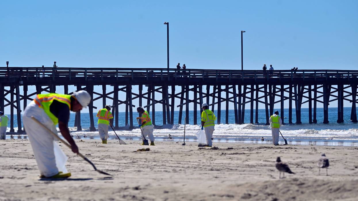 Workers clean oil from the sand