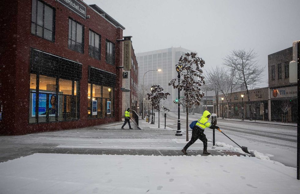 Workers clear the sidewalk of snow in downtown White Plains on Feb. 13, 2024