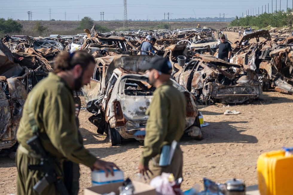 Workers from several agencies search through cars on Nov. 5, 2023, in Tkuma, Israel, at a site where all cars damaged or abandoned in the Oct. 7 Hamas attacks are collected.