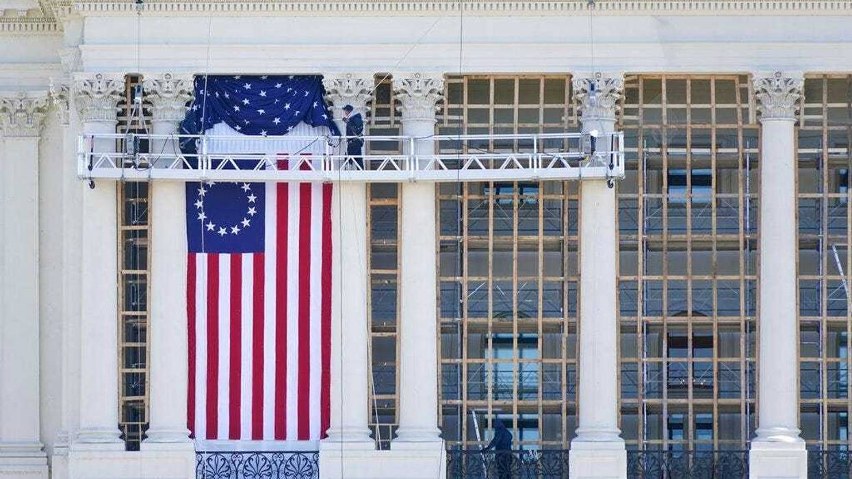 Workers install a flag on the West Front of the U.S. Capitol as preparations take place for President-elect Joe Biden's inauguration, Saturday, Jan. 9, 2021, in Washington.