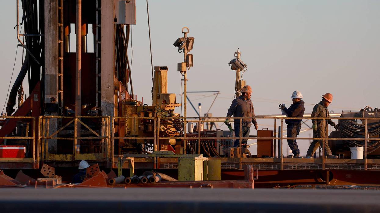 Workers on an oil drilling rig set up in the Permian Basin oil field on March 12, 2022, in Stanton, Texas.