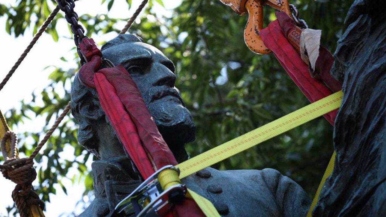 Workers remove a statue of Confederate General Thomas "Stonewall" Jackson from the Charlottesville and Albemarle County Courthouse Historic District July 10, 2021 in Charlottesville, Virginia. Initial plans to remove the statue, and one of Robert E. Lee, four years ago sparked the infamous “Unite the Right” rally where 32-year-old Heather Heyer was killed. (Photo by Win McNamee/Getty Images)