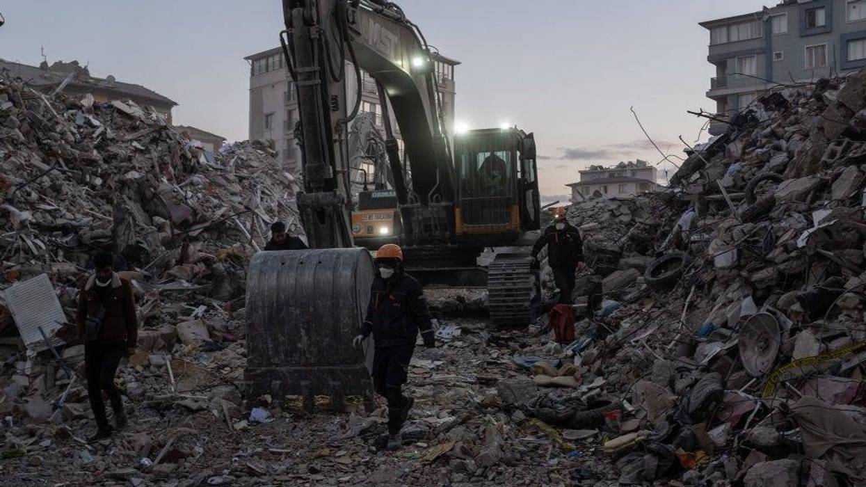 Workers walk past piles of rubble on February 15, 2023 in Hatay, Turkey. A 7.8-magnitude earthquake hit near Gaziantep, Turkey, in the early hours of February 6, followed by another 7.5-magnitude tremor just after midday.
