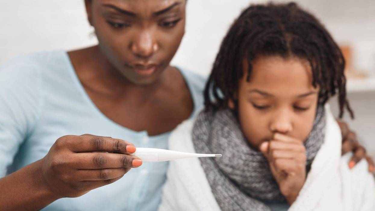 Worried mother looking at thermometer, ill daughter coughing