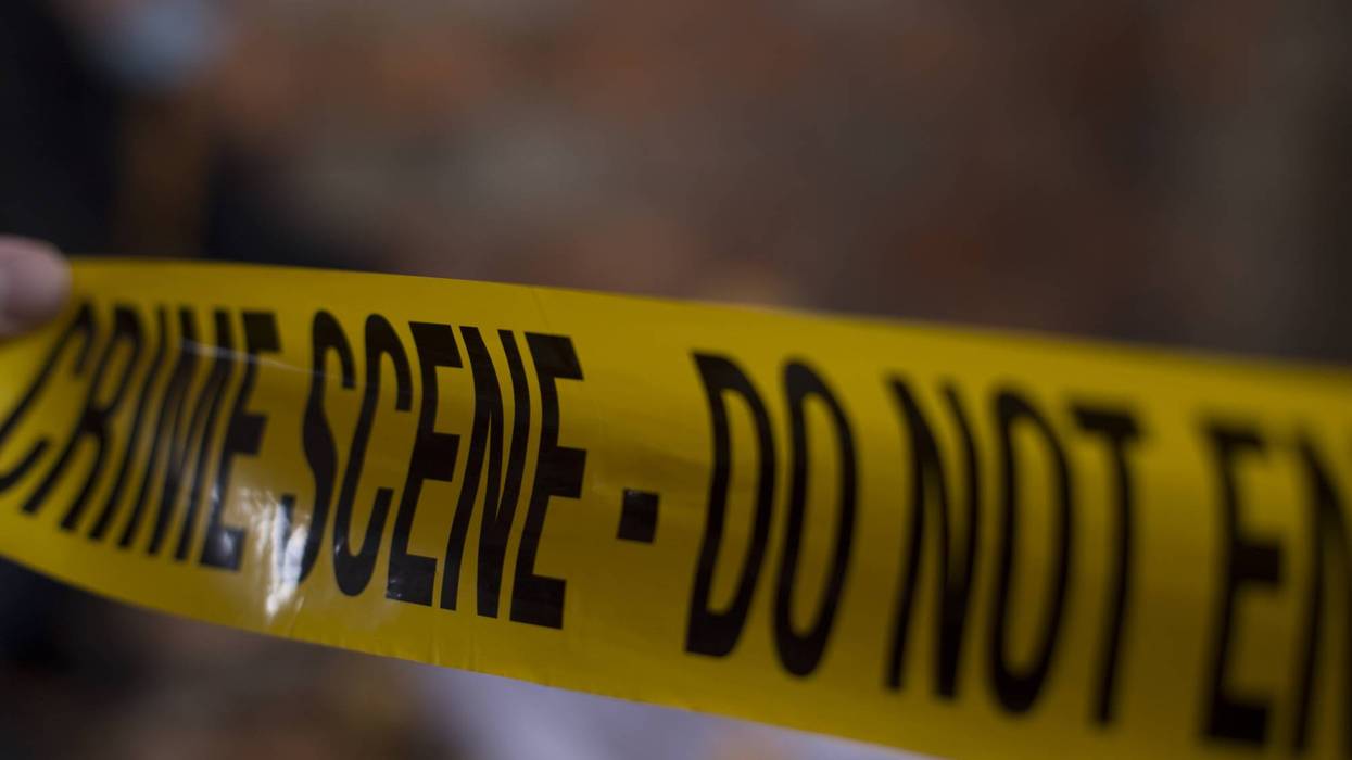 Yellow "CRIME SCENE - DO NOT ENTER" tape is held by a hand, with a blurred background.