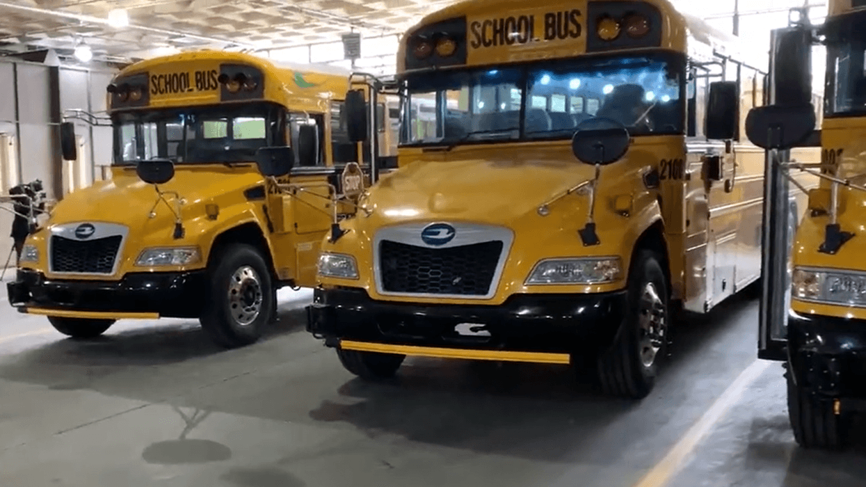 Yellow electric school bus plugged in at a charging station