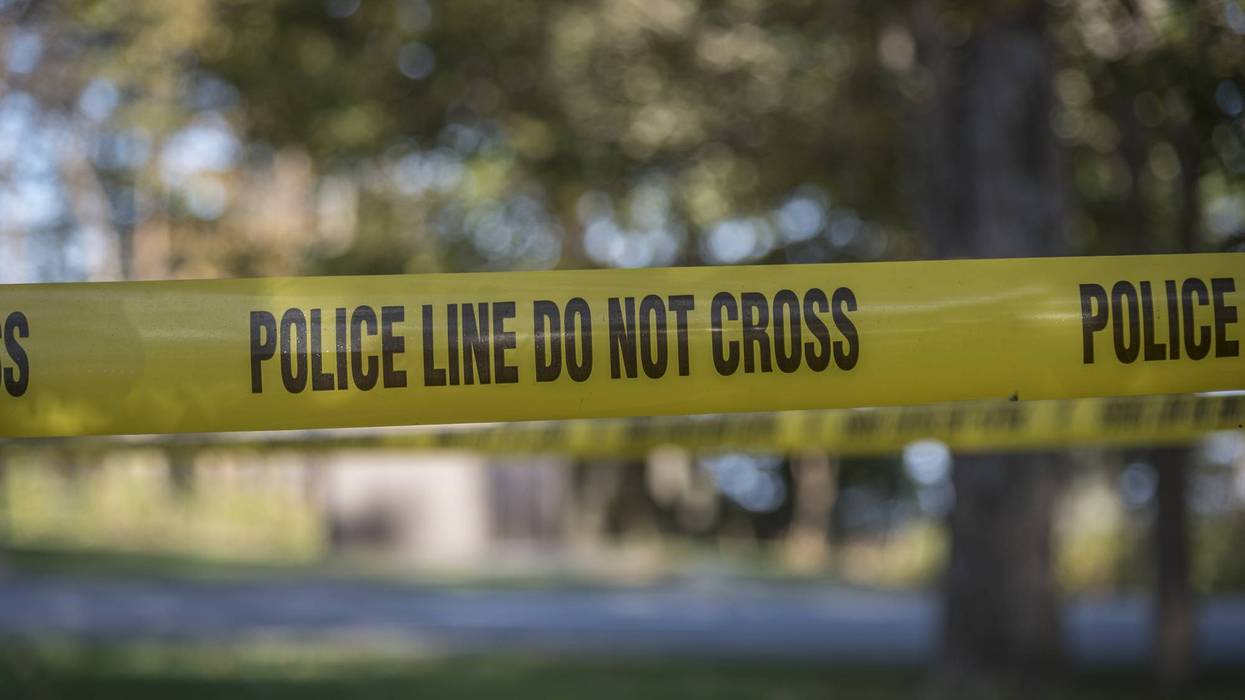 Yellow police tape reads 'POLICE LINE DO NOT CROSS' against a blurred outdoor background.